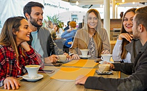 Group of people drinking cappuccino in a bar- Friends hanging out with each other and talking- Smilie boys ang girls having