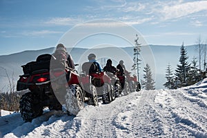 Group of people driving four-wheelers ATV bikes on snow in winter