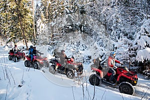 Group of people driving off-road four-wheelers ATV bikes in winter forest