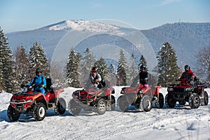 Group of people driving quad bikes at top of the mountain in winter