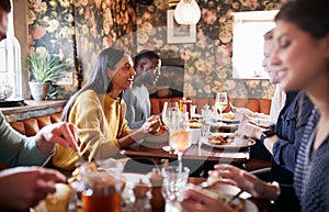 Group Of People Eating In Restaurant Of Busy Traditional English Pub