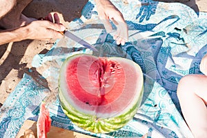 Group of people eating a watermelon on the beach