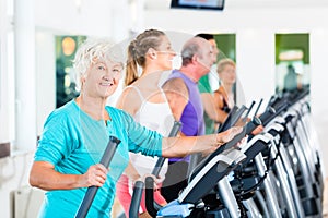 Group of people on elliptical trainer exercising in gym