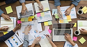 A group of people are engaged in a collaborative work session around a wooden