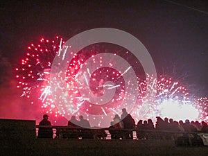 Group of people enjoying spectacular red fireworks show in a carnival or holiday