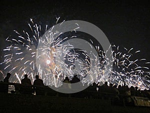 Group of people enjoying spectacular white fireworks show in a carnival or holiday