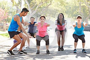 Group Of People Exercising InStreet With Personal Trainer