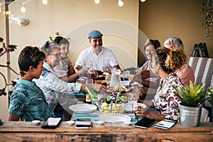 Group of people friends or family enjoy together dinner or lunch sitting at the table with food and drinks - happy people