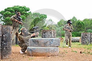 Group of people in full gear playing paintball on shooting range outdoor