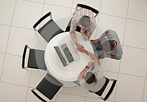 Group of people with gadgets sitting at a round table