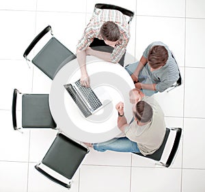 Group of people with gadgets sitting at a round table