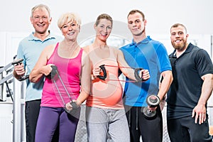 Group of people in gym with stretch bands and dumbbells