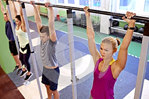 Group of people hanging at horizontal bar in gym