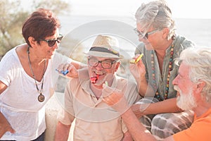 Group of people having fun together celebrating something happened - four seniors smiling and laughing at the beach photo