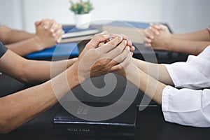 group of people holding hands in remembrance of god On the table there is a Bible, Respect, Spirituality and Religion. Christian