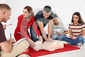 Group of people with instructor practicing CPR on mannequin at first aid class