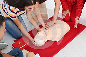 Group of people with instructor practicing CPR on mannequin at first aid class, closeup