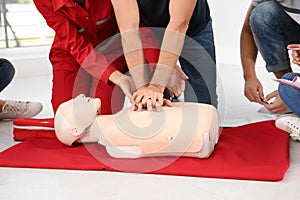 Group of people with instructor practicing CPR on mannequin at first aid class indoors