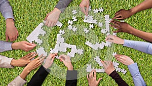 Group Of People Joining The White Puzzles On Grass
