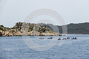 A group of people in kayaks travels near the Kekova Island. Tourists kayaking in the Mediterranean Sea