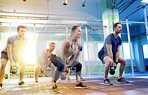 Group of people with kettlebells exercising in gym