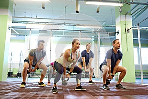 Group of people with kettlebells exercising in gym