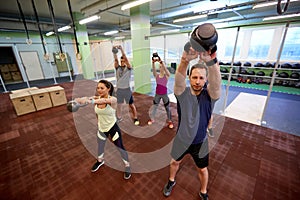 Group of people with kettlebells exercising in gym