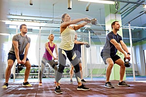 Group of people with kettlebells exercising in gym