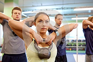 Group of people with kettlebells exercising in gym