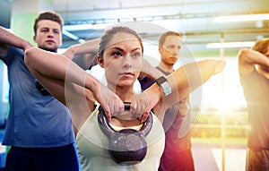 Group of people with kettlebells exercising in gym