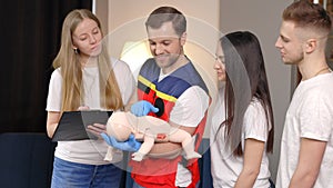 Group of people learning how to make first aid with dummy child during the training indoors