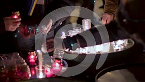 Group of people lighting dozens of candles in plastic glasses, light at night