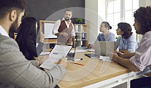 Group of people listening to a senior man while having a business meeting at work