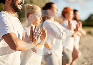 Group of people making yoga or meditating on beach