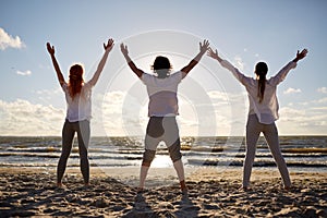 Group of people making yoga or meditating on beach