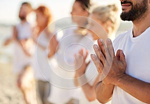 Group of people making yoga or meditating on beach