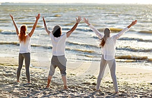 Group of people making yoga or meditating on beach