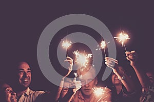 Group of people with mixed ages celebrate together new year or party event holiday. Family have fun with sparklers light by night