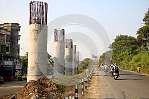 Group of people on a motorcycle down the road next to tall pillars