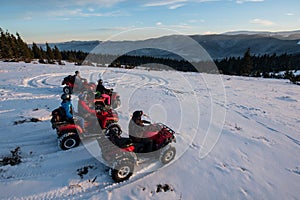 Group of people on off-road four-wheelers ATV bikes in the the mountains in winter evening