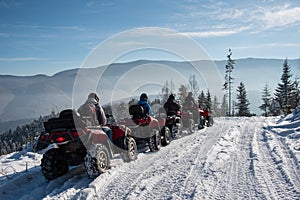 Group of people on off-road quad bikes in the winter mountains