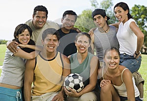 Group of people in park with woman holding soccer ball.