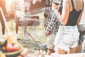 Group of people people having picnic barbecue in nature outdoor - Happy friends cooking meat and drinking wine in weekend summer