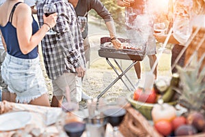 Group of people people having picnic barbecue in nature outdoor - Happy friends cooking meat and drinking wine in weekend summer