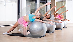 Group of people performs a side stretching exercise on a fitball
