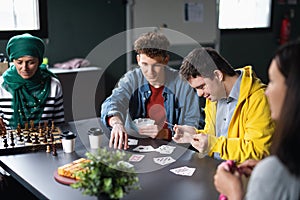 Group of people playing cards and board games in community center, inclusivity of disabled person.