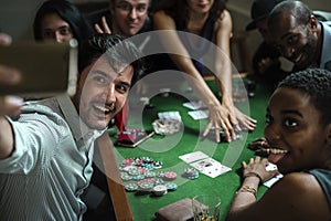 Group of people playing gamble in casino and taking selfie