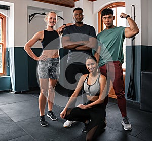 A group of people posing with arms around shoulders in a gym for a photo