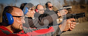 Group of people practice gun shoot on target on outdoor shooting range photo
