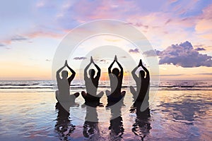 Group of people practicing meditation and yoga, beach, sunset, harmony